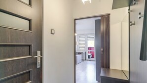 A hallway with a wooden door, a sliding glass door, and a dark-colored counter. - Spodek Comfort Studio (Katowice)