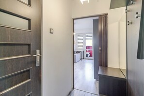 A hallway with a wooden door, a sliding glass door, and a dark-colored counter. - Spodek Comfort Studio (Katowice)