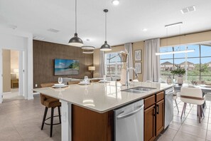 A modern kitchen with a large island, pendant lighting, and a view of the outdoors. - 8BR Themed Villa|Pool|Theater|RecRoom|Pet Friendly - Holiday Home (Kissimmee)