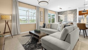 Ein modernes Wohnzimmer mit einem Ecksofa, einem Couchtisch, einer Lampe und Blick ins Freie.