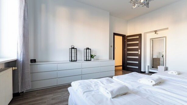 Une chambre d’hôtel moderne avec un grand lit, une table de chevet, un miroir et une fenêtre avec des rideaux.