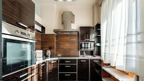 Une cuisine moderne dotée d’appareils électroménagers intégrés, de meubles de cuisine en bois foncé et d’une grande fenêtre agrémentée de rideaux légers.