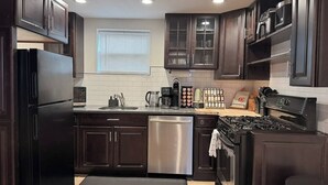Una cocina moderna con armarios de madera oscura, electrodomésticos de acero inoxidable y encimera negra.