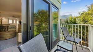 Un salon moderne doté d’une grande porte-fenêtre coulissante donnant sur un balcon aménagé avec du mobilier d’extérieur.