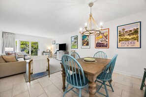 Un salon moderne comprenant un coin repas, un téléviseur et des œuvres d’art accrochées aux murs.