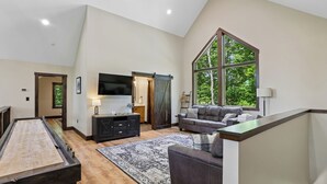 Ein geräumiges Wohnzimmer mit Billardtisch, einem großen Fenster und einem modernen Kamin.