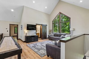 Ein geräumiges Wohnzimmer mit Billardtisch, einem großen Fenster und einem modernen Kamin.