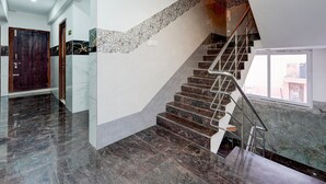 A modern interior with a marble staircase, a wooden door, and a view through a window.