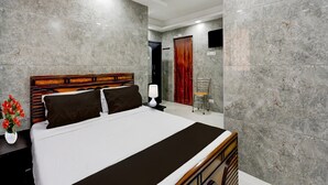 A modern hotel room with a large bed, a nightstand, a lamp, and a chair.