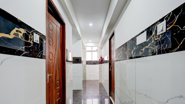 A hallway with marble walls, wooden doors, and a fire extinguisher on the wall.
