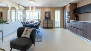 Un salon moderne comprenant un coin repas, une cuisine avec un four encastré et une grande fenêtre offrant une vue dégagée.