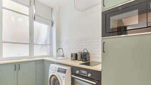 A compact kitchen with a washing machine, a microwave, and a toaster. - Bright Cosy Suite Paris 16th Steps From Seine (Paris)