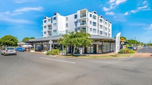 A multi-story hotel with a modern design, featuring balconies, a covered outdoor seating area, and a clear sky. - Platinum Apartments -  Unit 22 (Bargara)