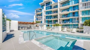 A modern hotel with a swimming pool, multiple balconies, and outdoor seating. - Dual Living, Pool, Gym, Sleeps 8, Parking (Bargara)