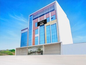 Un edificio moderno con fachada de vidrio, un letrero que dice 'Collection' y una entrada de metal.