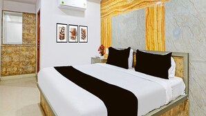 A hotel room with a bed, a wall-mounted air conditioner, and a marble-patterned wall.