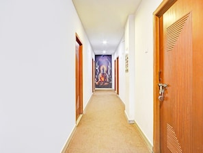 Un pasillo de hotel con puertas de madera, piso alfombrado y un mural en la pared.