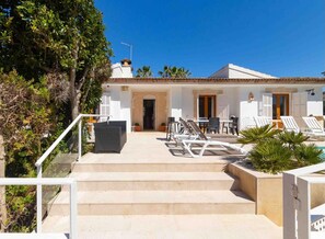 A villa with a pool, outdoor seating, and steps leading to the entrance.