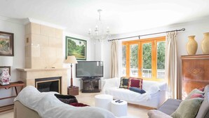 Una sala de estar con chimenea, televisión, sofá y una ventana con cortinas.