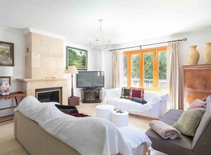 Una sala de estar con chimenea, televisión, sofá y una ventana con cortinas.