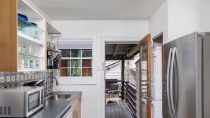 A compact kitchen with a built-in microwave, stainless steel appliances, and a sliding door leading to a balcony.