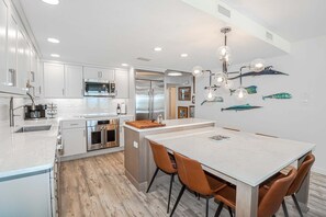 A modern kitchen with white cabinets, stainless steel appliances, and a central island with seating. - Sand Dollar 3-305: Direct Oceanfront 3/2 Condo, Luxury in St. Augustine Beach! (St. Augustine)