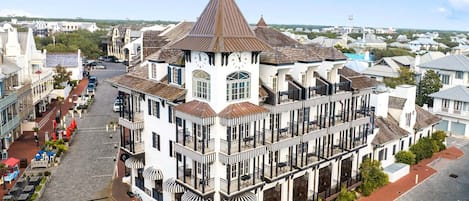 A historic building with a prominent clock tower, multiple balconies, and a central courtyard with outdoor seating.