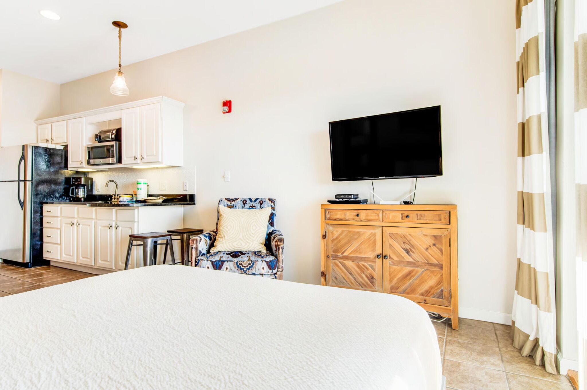 Une chambre d’hôtel équipée d’un lit, d’une kitchenette, d’une télévision et d’une chaise.