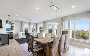 Ein geräumiger Wohnbereich mit Esstisch, Sofas und großen Fenstern mit Blick ins Freie.