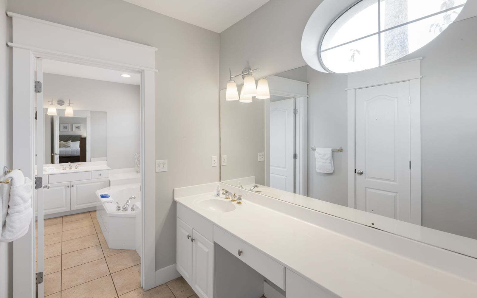 A modern bathroom with a large mirror, a white vanity, and a shower area.