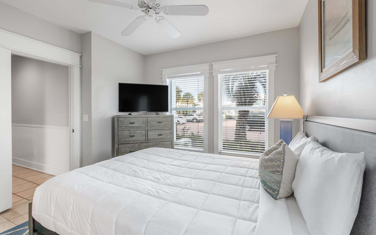A bedroom with a bed, a dresser, a television, and a ceiling fan.