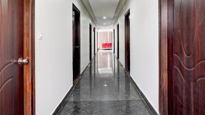 A hallway with wooden doors, a red couch, and a number '205' on a door. - Deluxe Super Collection O Banaswadi (Bengaluru)