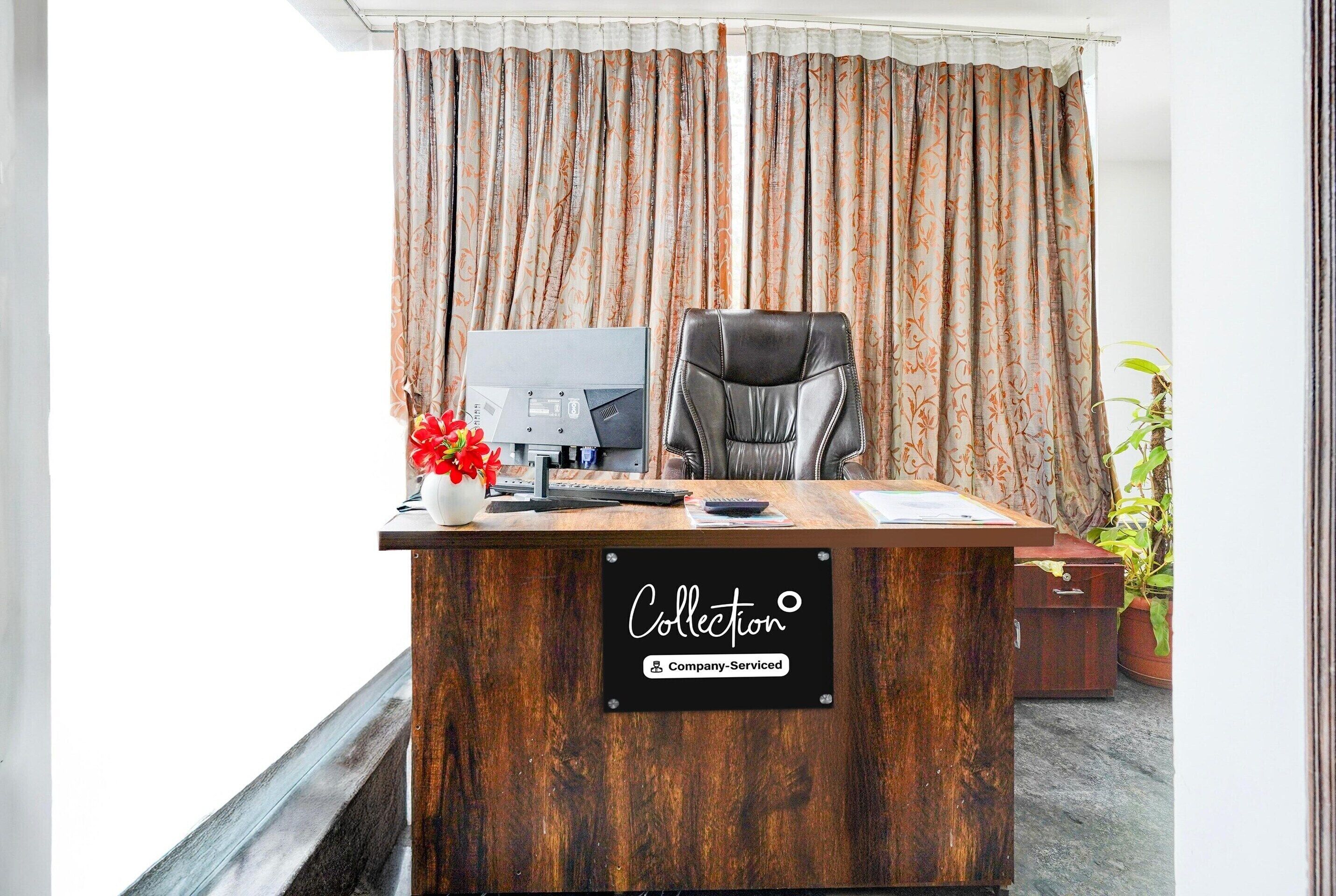 A reception desk with a sign reading 'Collection Company-Serviced,' a computer, a telephone, and a chair.