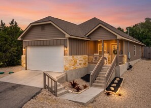 A two-story house with a garage, a front porch with a railing, and a staircase leading to the front door. - 3BR Modern Home in Canyon Lake | 1 mile from Public Boat Ramp (Canyon Lake)