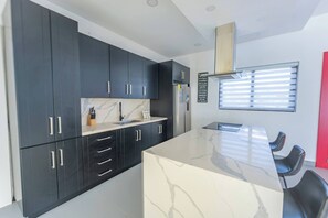 Una cocina moderna con armarios oscuros, una encimera de mármol y una estufa empotrada.