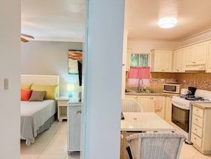 A bedroom with a bed, bedside table, lamp, and a view of the kitchen. - Garden Condos APT 44 - Comfy 1BR APT in Sosua! (Sosúa)