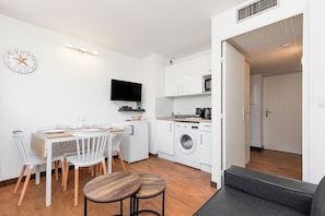 A compact kitchen with a dining area, a washing machine, and a flat-screen TV. - Upstays charming t2 renovated balcony and  pool (Cannes)