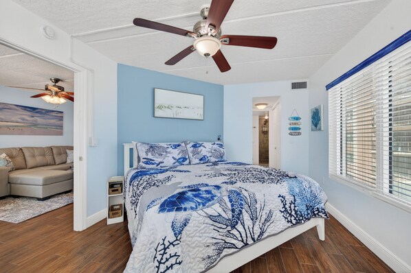 A bedroom with a bed, ceiling fan, and artwork on the wall. - Beach Vibes at Southpoint (Daytona Beach)