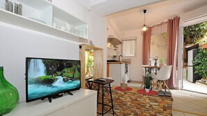Ein modernes Wohnzimmer mit Fernseher, Essbereich und Küche.