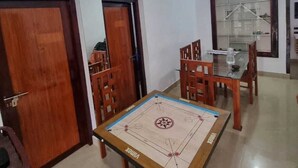 A room with a foosball table, a ceiling fan, and a dining area with chairs and a table.