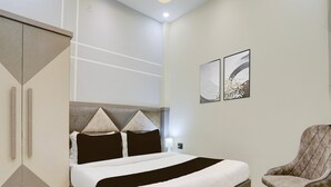 Et moderne hotelværelse med en seng, en stol og kunst på væggen.
