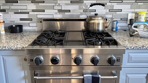 A kitchen with a stainless steel stove, oven, and a checkered towel hanging on the oven handle.