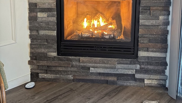 A fireplace with a stone facade, a television mounted above it, and a sign that reads 'QUIET PLEASE! BEAR HIBERNATING' on the wall.
