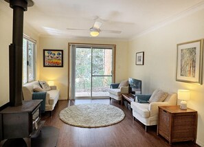 A living room with a fireplace, two sofas, a TV, a round rug, and a ceiling fan.
