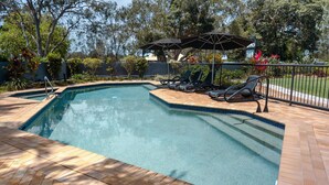 Una piscina con sillones de descanso y una sombrilla.