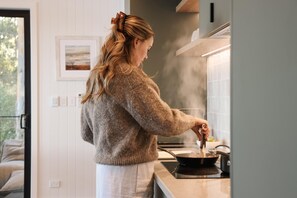 A person cooking in a modern kitchen with a view of the outdoors.