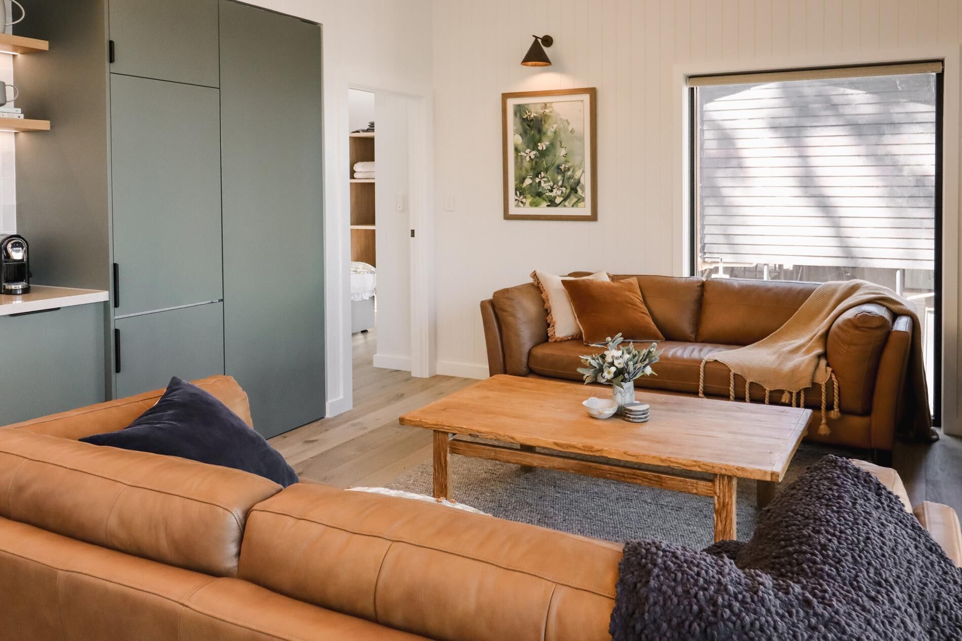 A living room with a sofa, a coffee table, a couch, and a painting on the wall.