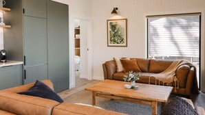 Una sala de estar con un sofá, una mesa de centro, un sillón y un cuadro en la pared.