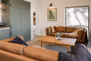 Un salon avec un canapé, une table basse, un divan et un tableau accroché au mur.