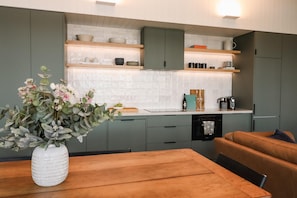 Une cuisine moderne avec des meubles gris, un plan de travail en bois et un coin repas comprenant une table et un banc.
